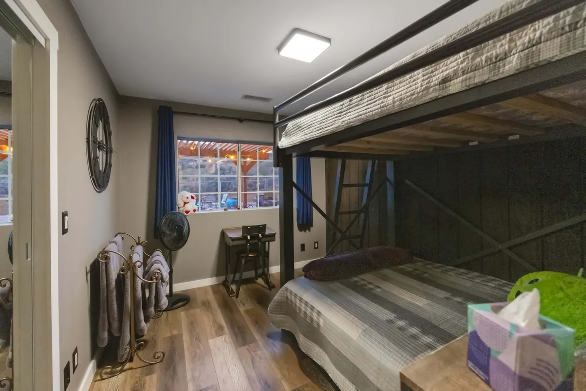 A comfortable bedroom with a bunk bed, window with curtains, a small desk and chair, and towel rack. The cozy setting is ideal for families or groups, offering flexible sleeping arrangements and thoughtful touches.
