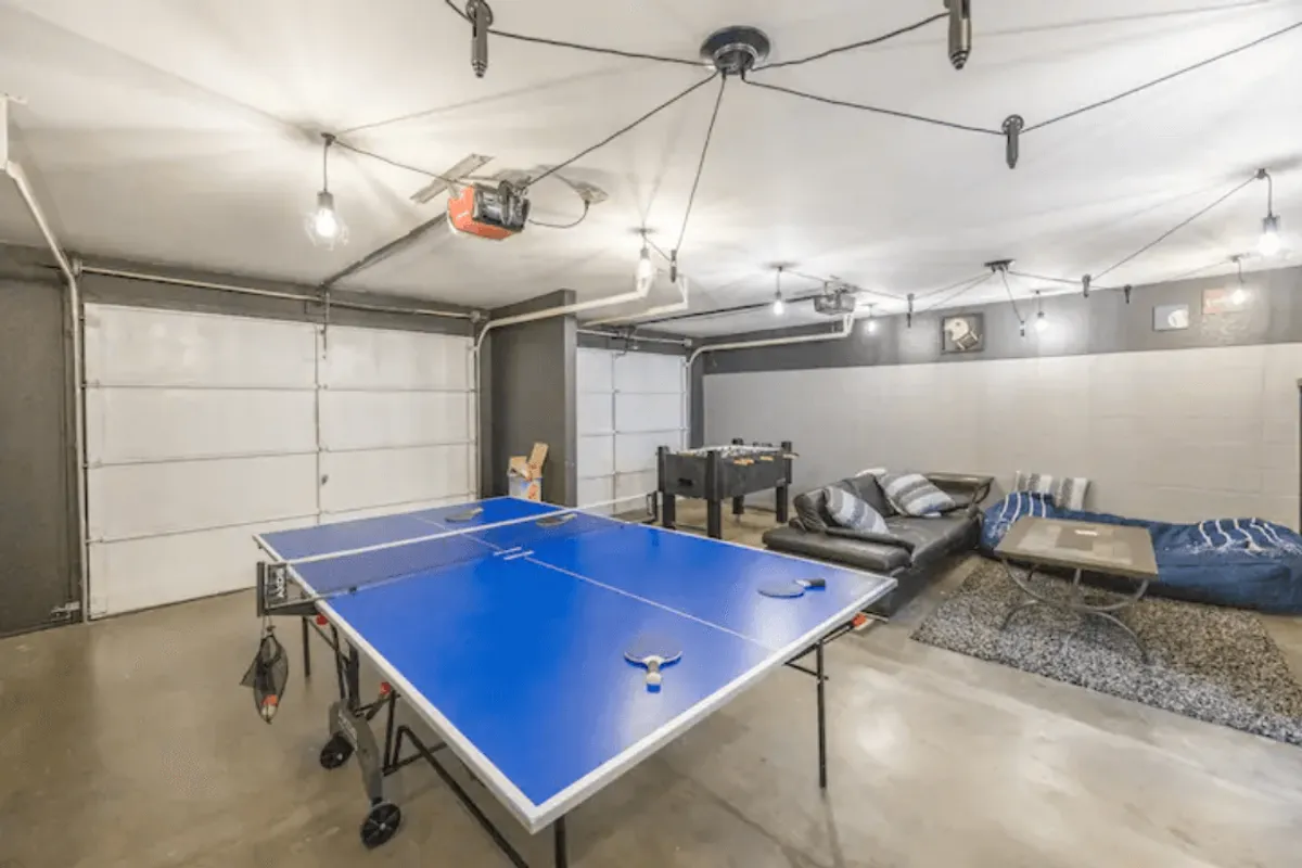 A vibrant game room outfitted with a ping pong table, foosball table, bean bags, and a sofa, designed for relaxed socializing, friendly competitions, and laid-back movie nights. The space exudes a fun, relaxed energy ideal for group engagement.